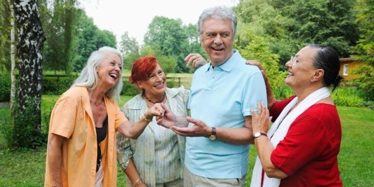 Group of Seniors Laughing and Talking Outdoors at Independent Living Facility