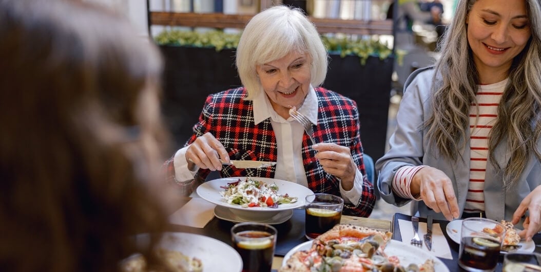 Senior Woman with Family Enjoying Meal at Independent Living Facility