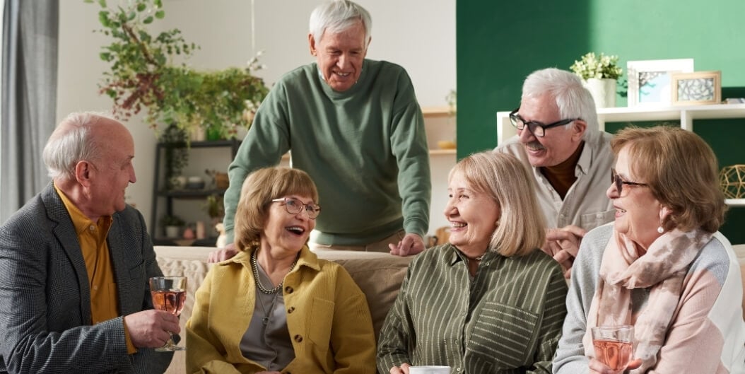Group of Elderly Friends Laughing Together over Drinks at Independent Living Facility
