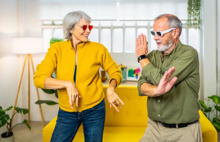 Elderly Couple Dancing Playfully Indoors Wearing Sunglasses at Independent Living Facility
