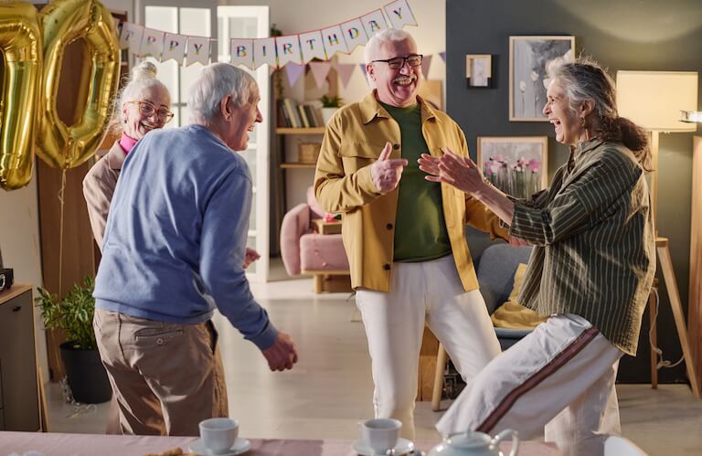 Elderly Friends Dancing Together at Festive Birthday Party at Independent Living Community
