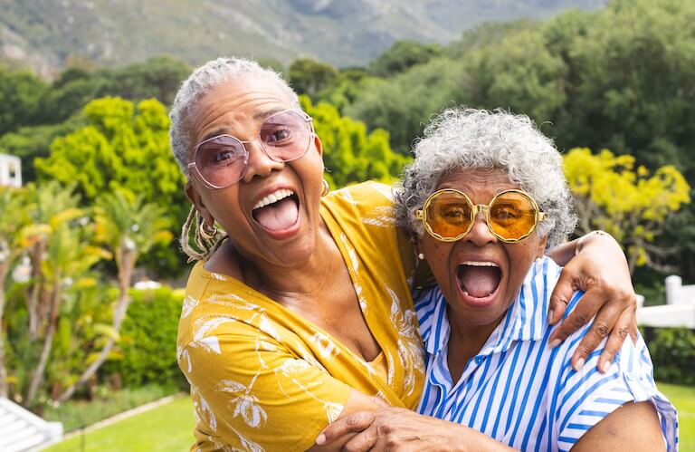 Two Elderly Women Laughing Joyfully Together Outdoors at Independent Living Facility