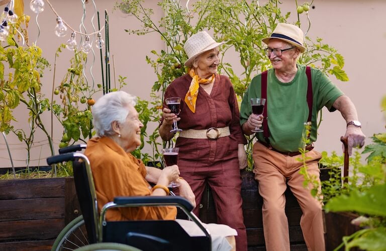 Elderly Residents Gardening and Watering Plants Together Outdoors at Independent Living Community