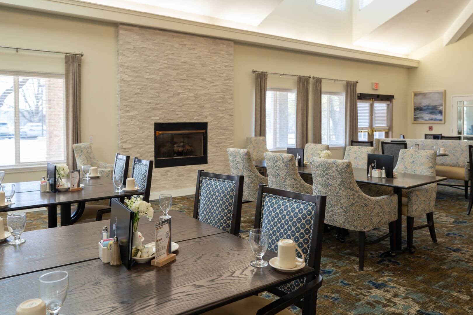 Warm Dining Room with Stone Fireplace and Cushioned Chairs in Our Independent Living Community