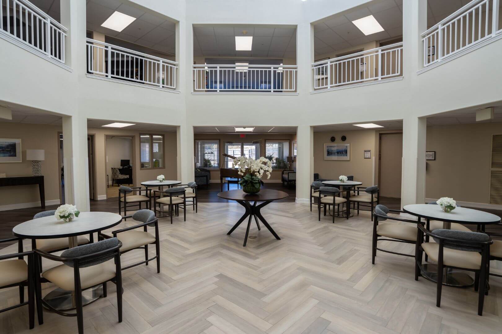 Grand Two-Story Atrium with Bistro Tables and Floral Centerpiece in Our Independent Living Community